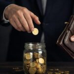 Руки с золотыми монетами и кошельком, символизирующие накопление и траты денег.
